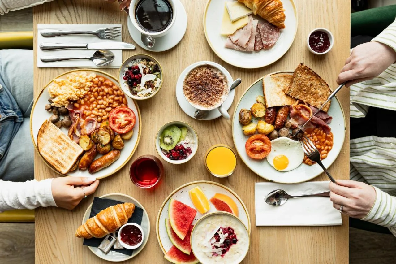a table with plates of breakfast food on it at Leonardo Hotel Manchester Piccadilly in Manchester