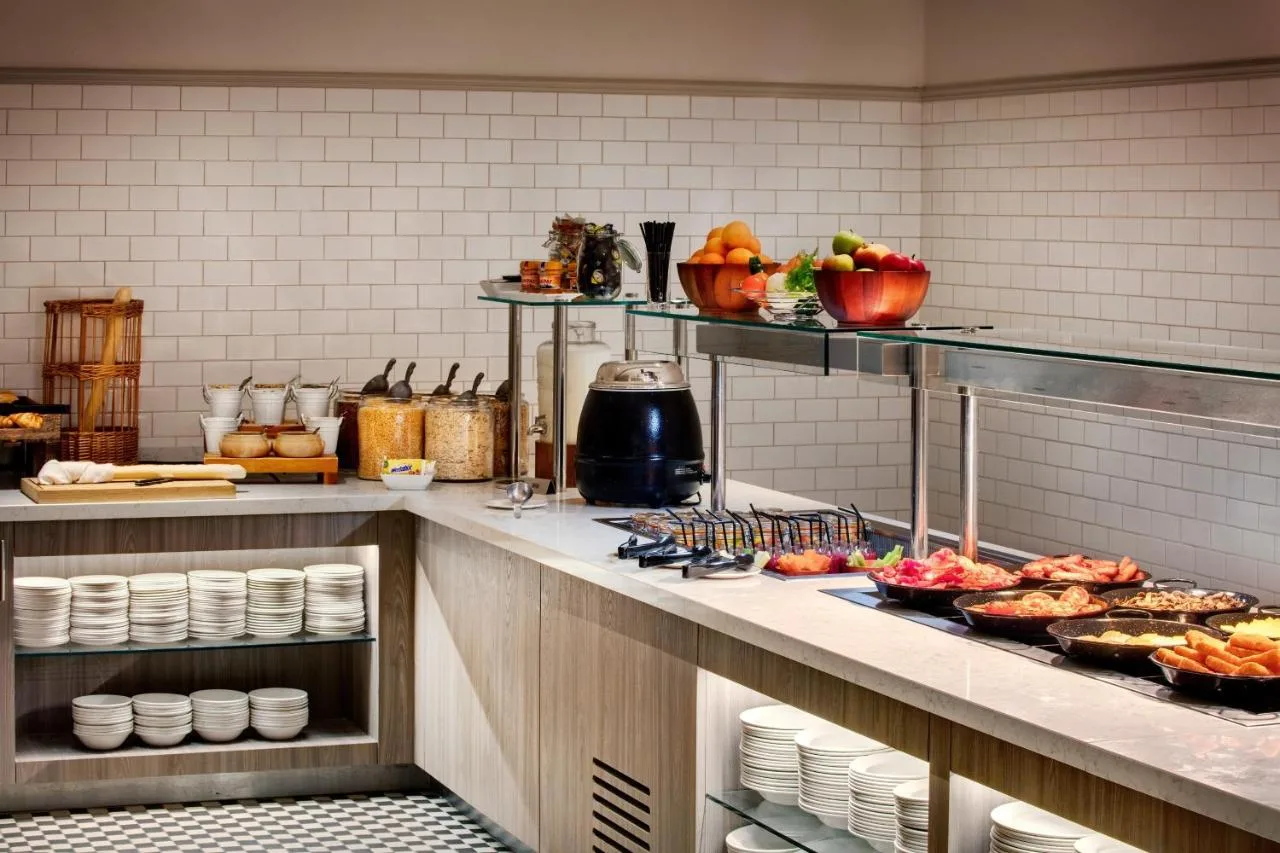 a kitchen with food on a counter in a restaurant at Leonardo Hotel Manchester Piccadilly in Manchester