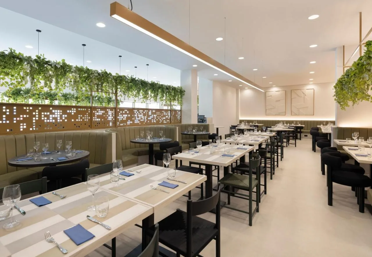 a restaurant with white tables and black chairs at Leonardo Hotel Manchester Piccadilly in Manchester