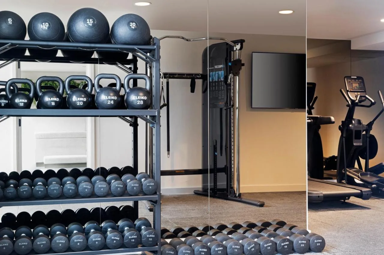 a gym with a rack of dumbbells and a tv at Leonardo Hotel Manchester Piccadilly in Manchester